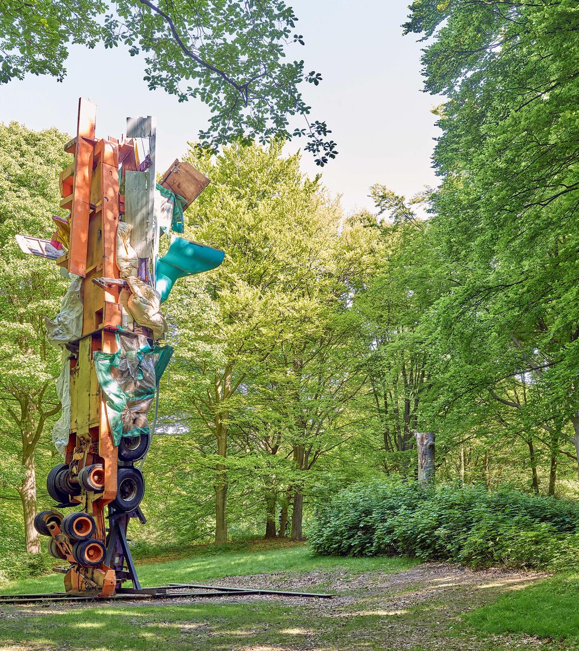 Auf einer Waldlichtung steht eine moderne, bunte Skulptur.