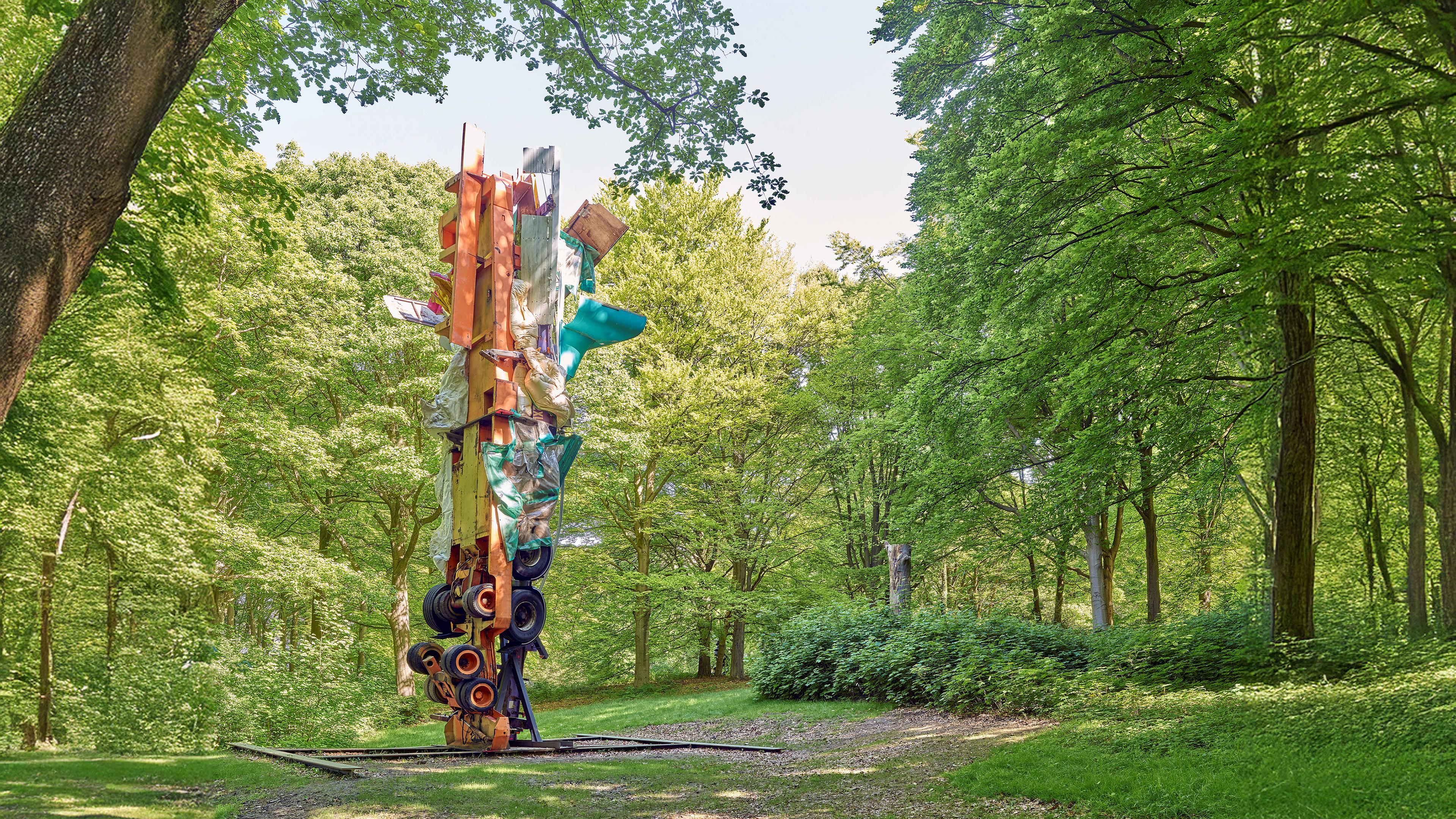 Auf einer Waldlichtung steht eine moderne, bunte Skulptur.