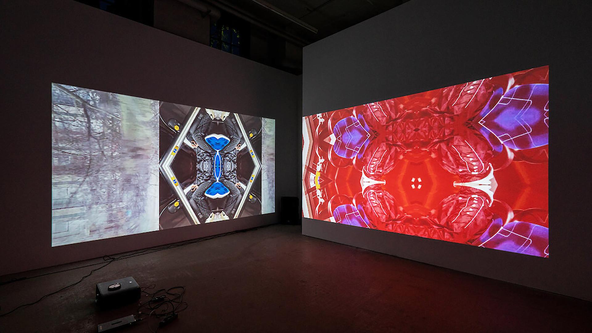 In einem abgedunkelten Ausstellungsraum sieht man zwei Videoinstallationen.