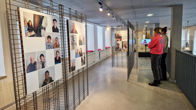 In einem Ausstellungsraum schauen sich zwei Frauen die Fotowände an.