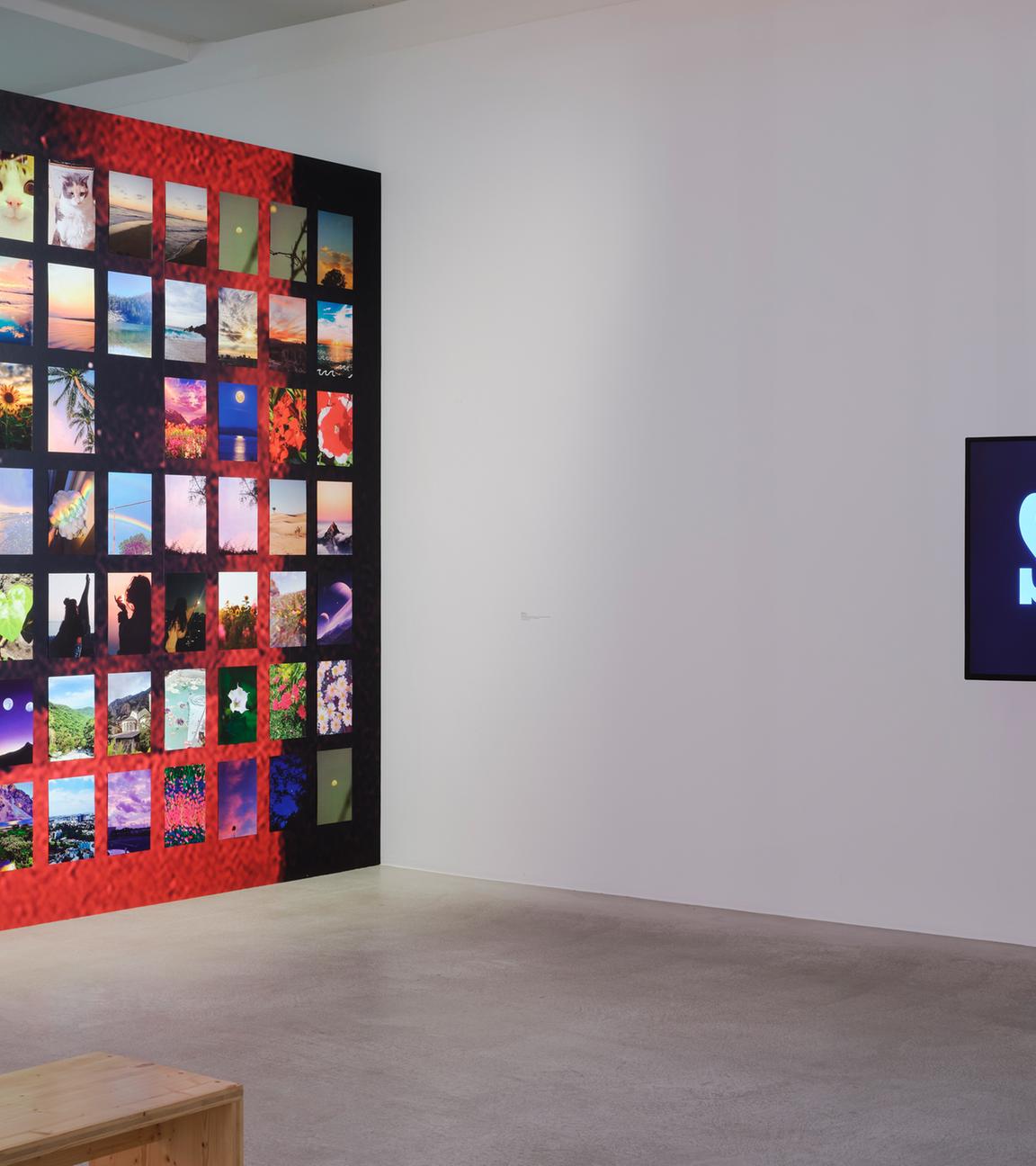 In einem Ausstellungsraum befinden sich links viele, bunte Fotos an einer Wand. Rechts ist ein Schild mit dem Wort "Strike" zu sehen.