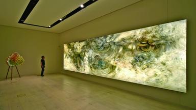 In einem Ausstellungsraum sieht man ein modernes Gemälde, das an Wellen und Wolken erinnert.