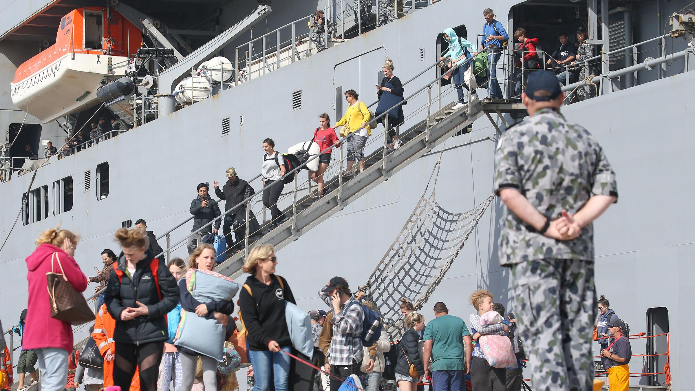 Evakuierte Australier und Touristen gehen vom Schiff im Hafen von Hastings, Australien.