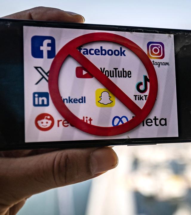 Auf diesem am 18. Juni 2026 in Dubai aufgenommenen Symbolfoto zeigt ein Mobiltelefon die Logos von Social-Media-Plattformen zusammen mit einem Verbotszeichen. Die Vereinigten Arabischen Emirate kündigten ein Social-Media-Verbot für Kinder unter 15 Jahren an.