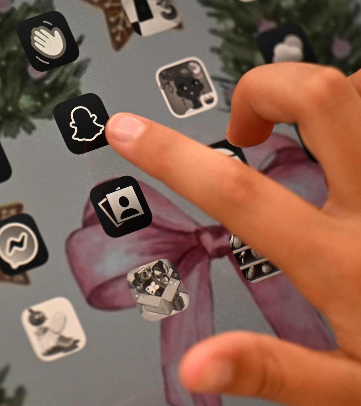 Eine hand zeigt auf das Icon der Social-Media-App Snapchat auf einem Tablet.