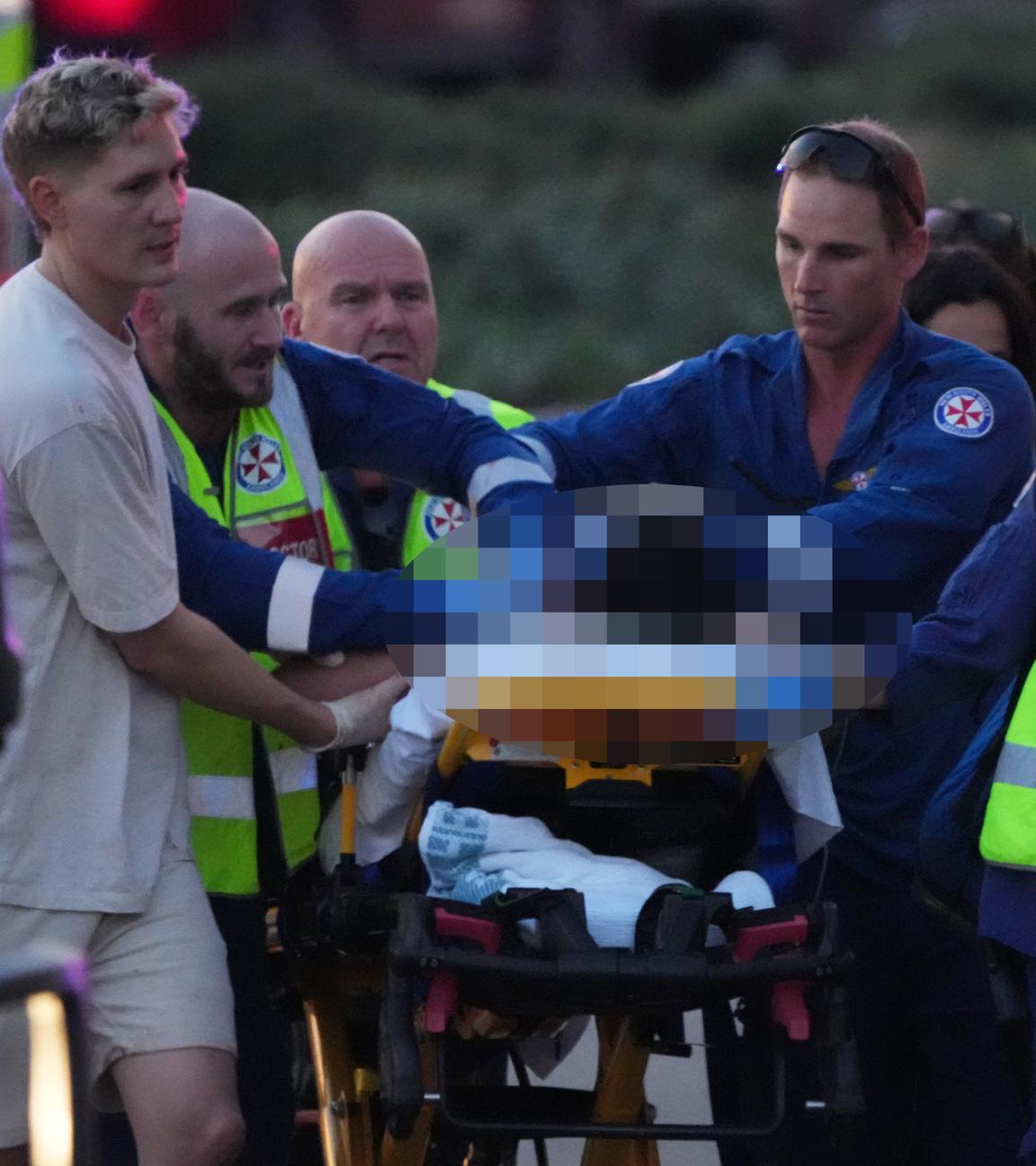 Australien, Sydney: Rettungskräfte transportieren eine Person nach einer gemeldeten Schießerei am Bondi Beach in Sydney auf einer Trage ab.