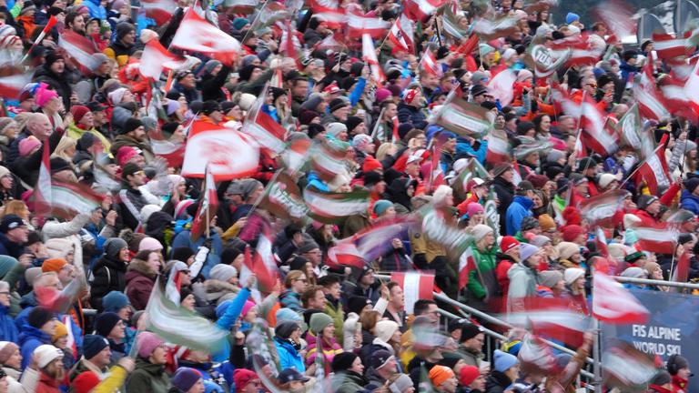 Die Menge schwenkt am Mittwoch, den 12. Februar 2025, im Zielbereich einer Abfahrt eines Kombinationswettbewerbs der Herrenmannschaft bei den Alpinen Ski-Weltmeisterschaften in Saalbach-Hinterglemm, Österreich, Fahnen. 
