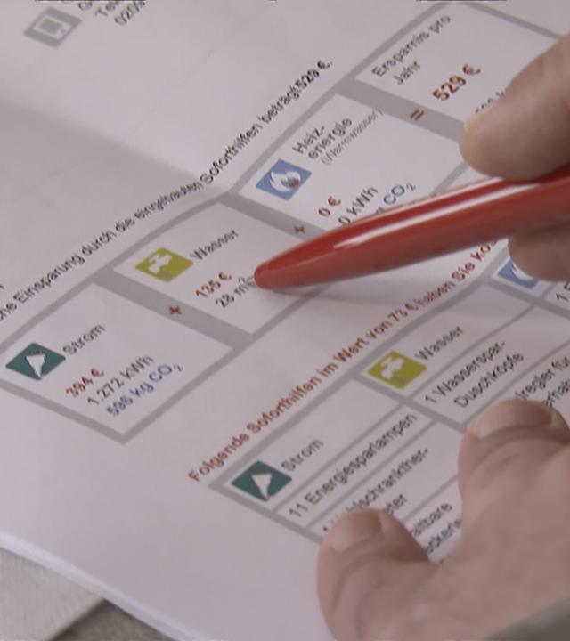 Jemand zeigt mit einem Stift auf eine ausgedruckte Tabelle.