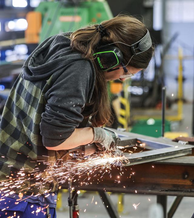 Symbolbild: Eine Auszubildende zum Metallbauer arbeitet im AusbildungsCampus Butzweilerhof in Köln mit einem Schleifgerät. 