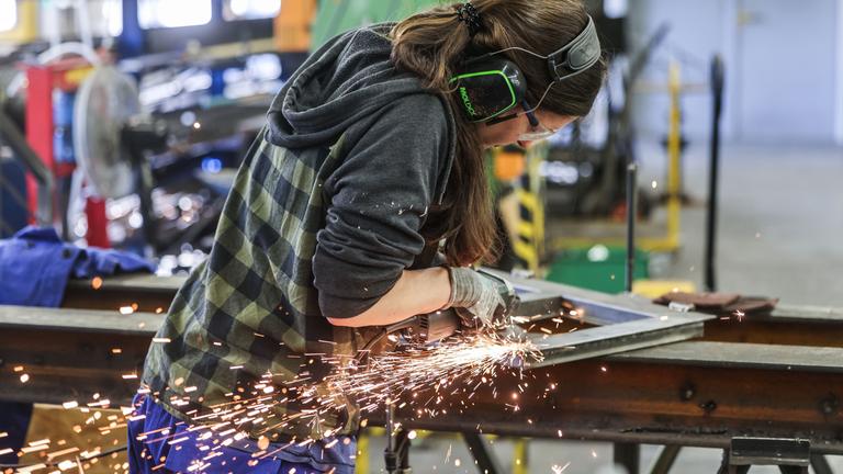 Symbolbild: Eine Auszubildende zum Metallbauer arbeitet im AusbildungsCampus Butzweilerhof in Köln mit einem Schleifgerät. 