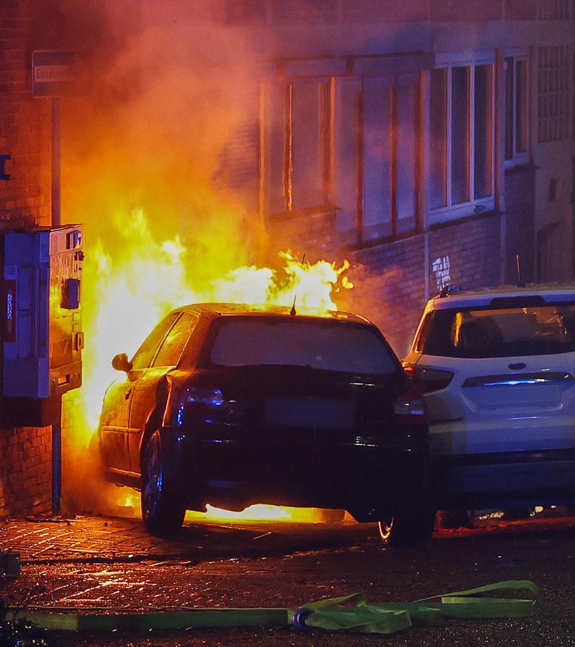 Ein brenndes Auto steht vor einem brennenden Stromkasten