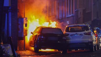 Ein brenndes Auto steht vor einem brennenden Stromkasten