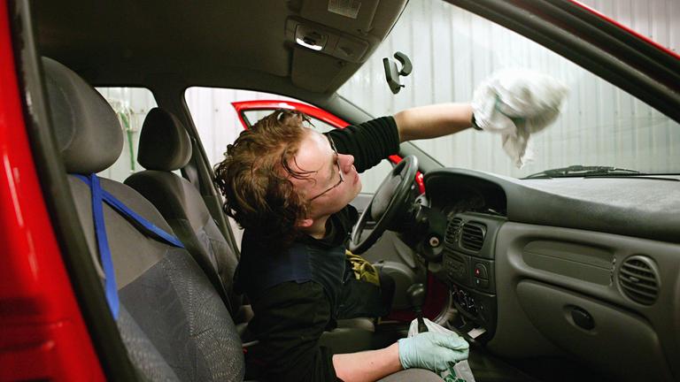Mitarbeiter putzt Auto.