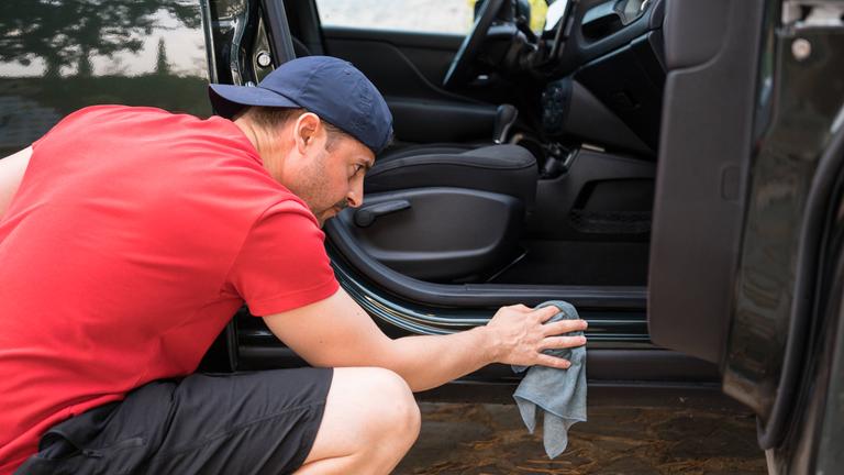 Ein Mann reinigt die Gummidichtung an der Türe seines SUVs.