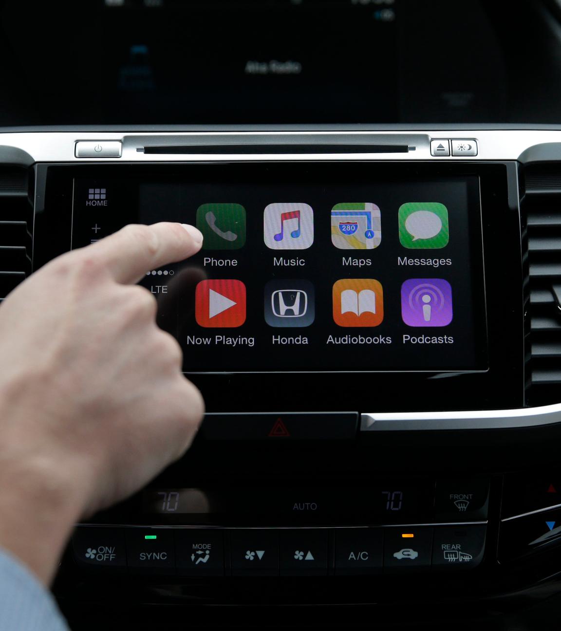 Ein Mann im Auto steuert CarPlay.