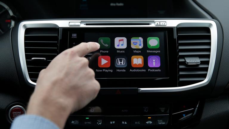 Ein Mann im Auto steuert CarPlay.