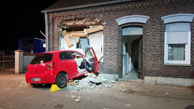  Ein Kleinwagen steckt in einer zertrümmerten Hauswand.