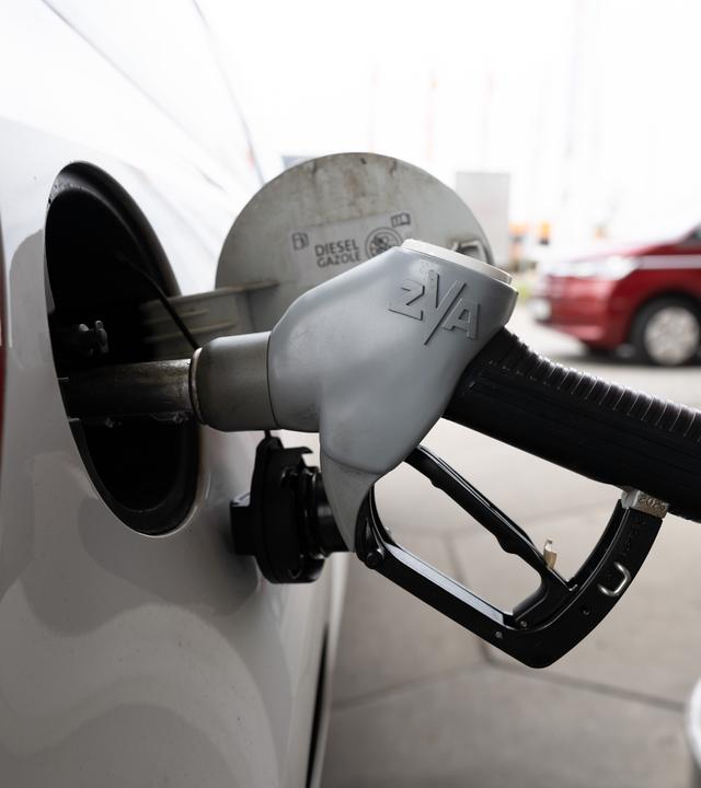 Ein Tankstutzen steckt an einer Tankstelle in der Tanköffnung eines Fahrzeugs.