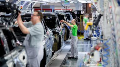 Mitarbeiter überprüfen im Lichttunnel der Lackiererei im Werk von Volkswagen den Lack einer Karosserie