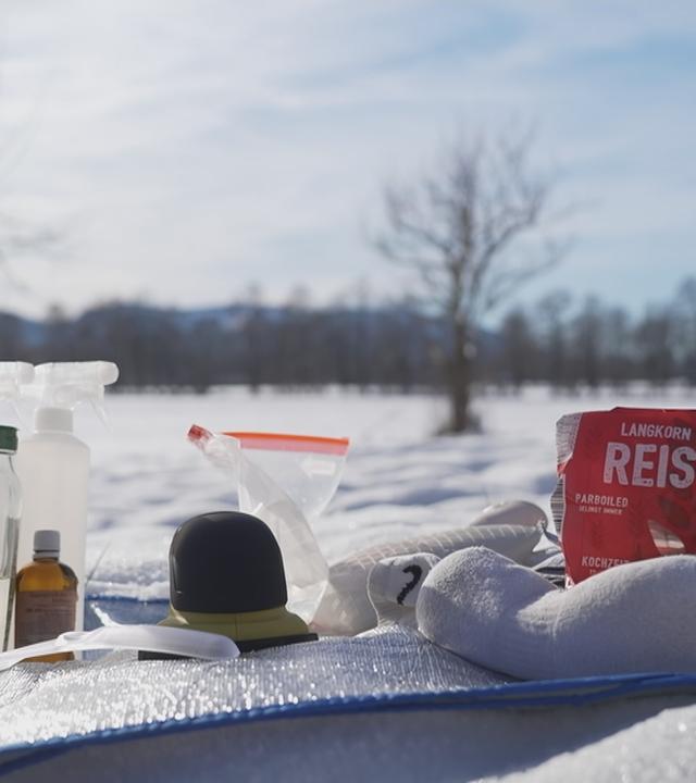 Mehrere Enteisungsmittel und Werkzeuge auf schneebedecktem Boden.