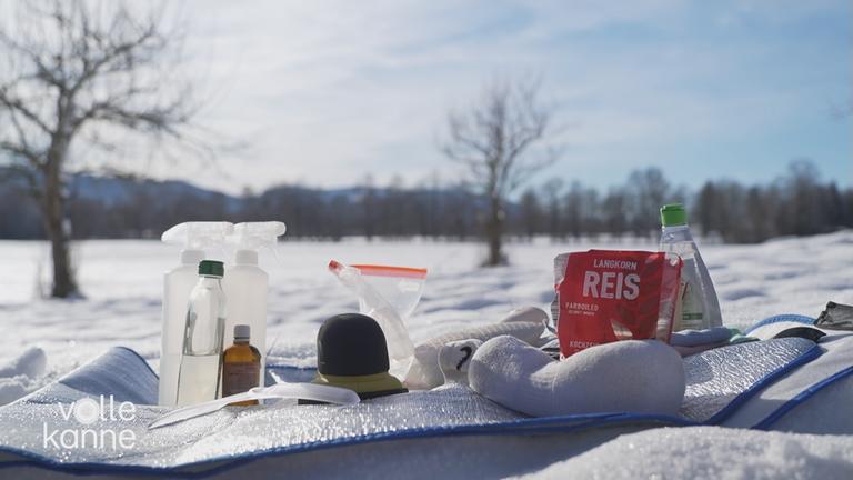 Mehrere Enteisungsmittel und Werkzeuge auf schneebedecktem Boden.