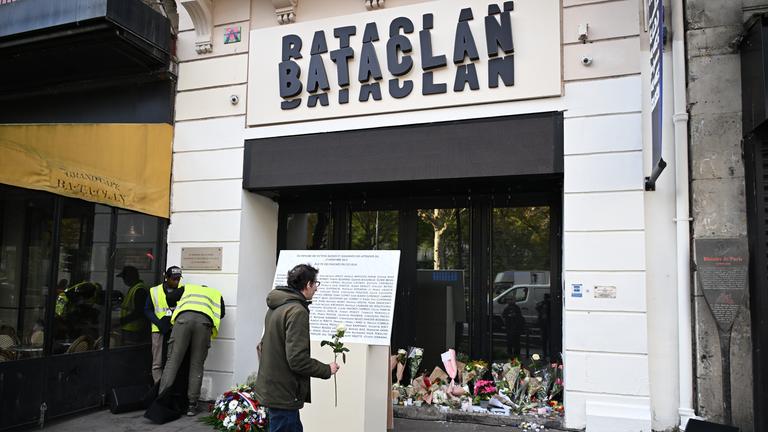 Man erkennt einen Mann der vor dem Bacatlan eine weiße Rose hält