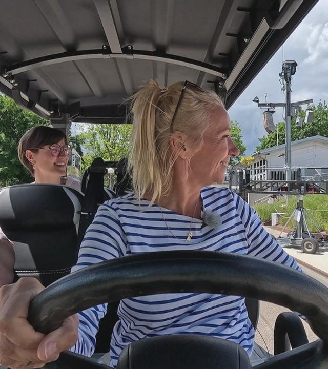 Andrea Kiewel fährt mit Golfcar über Gelände vom ZDF-Fernsehgarten.