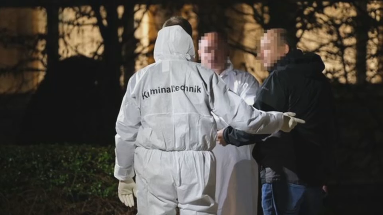 Spurensicherung arbeitet vor Klinik, Mann in weißem Schutzanzug mit Aufdruck "Polizei"- Nachtbilder