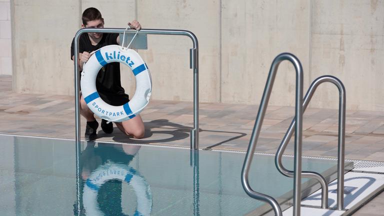 Bademeister Raiko Jantsch befestigt einen Rettungsring am Beckenrand des Sportbades am Klietz in Quedlinburg.