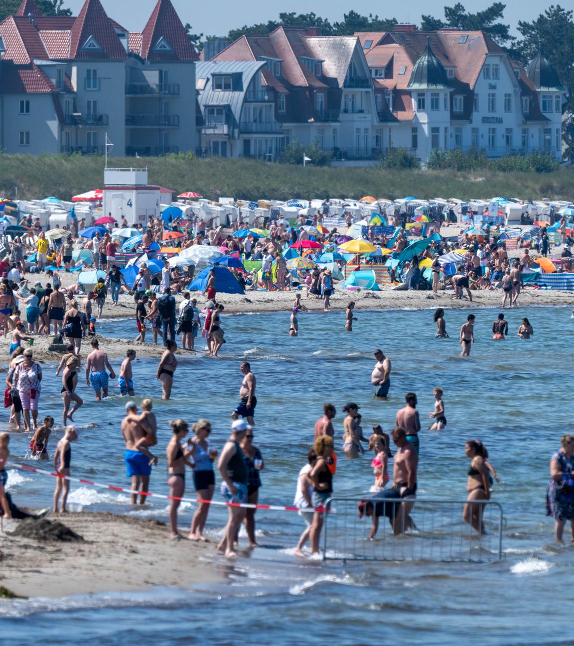 Touristen spazieren und baden am Strand der Ostsee.