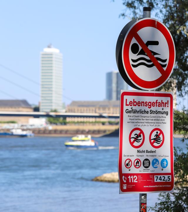 Ein Schild am Ufer des Rheins warnt vor dem Schwimmen und Baden im Fluss.
