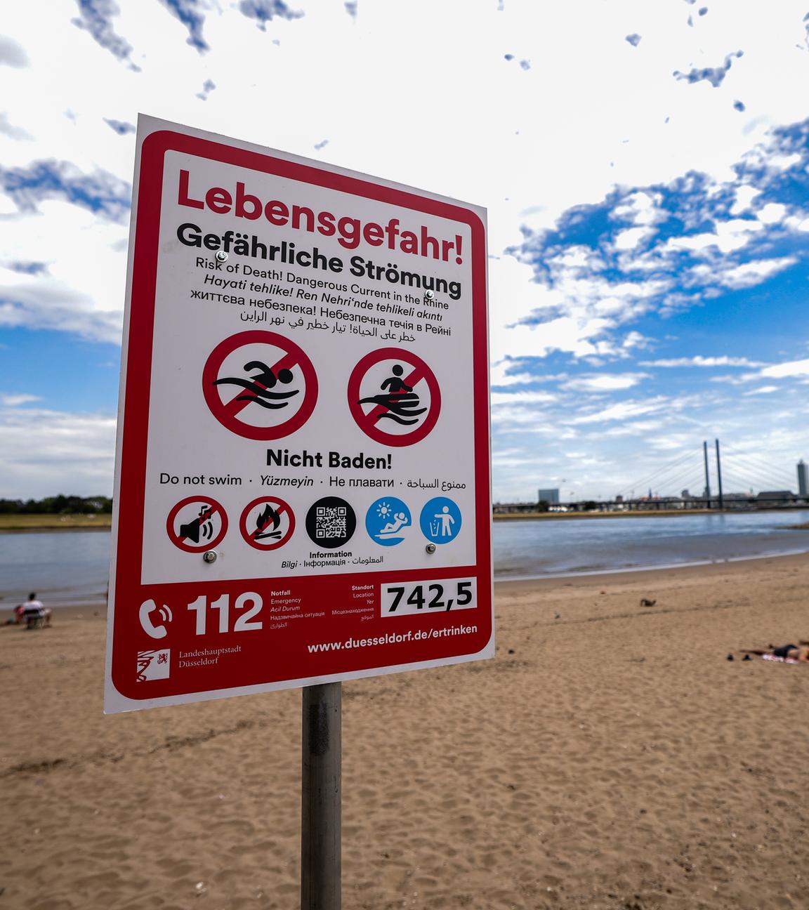 Nordrhein-Westfalen, Düsseldorf: Ein Hinweisschild am Paradiesstand in Düsseldorf weist auf die Gefahren beim Schwimmen im Rhein hin.