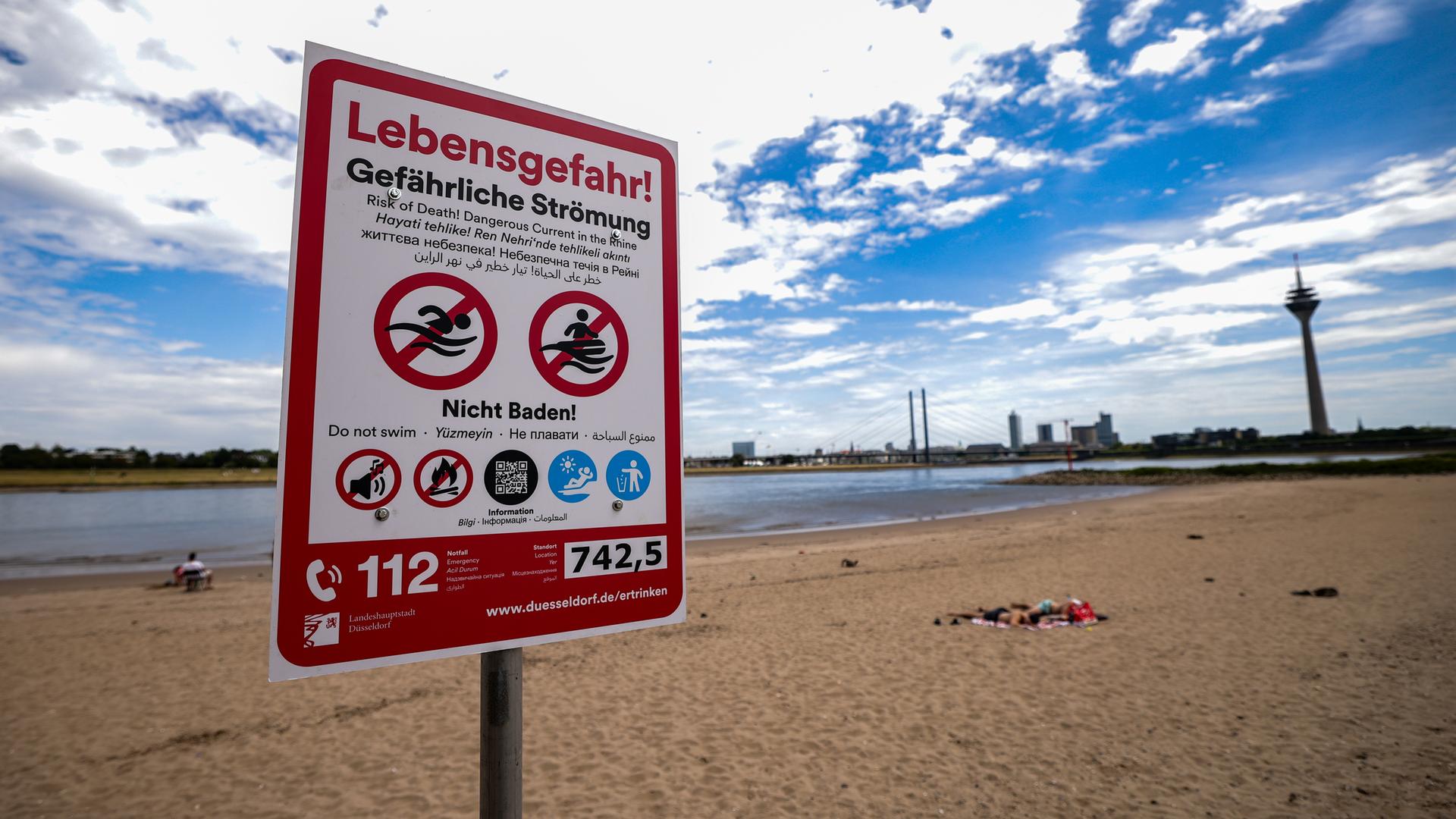 Nordrhein-Westfalen, Düsseldorf: Ein Hinweisschild am Paradiesstand in Düsseldorf weist auf die Gefahren beim Schwimmen im Rhein hin.