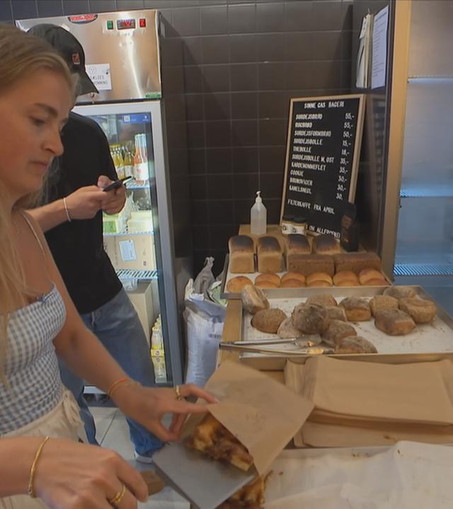 Frau steht beim Baecker an der Kasse und bedient sich selbst
