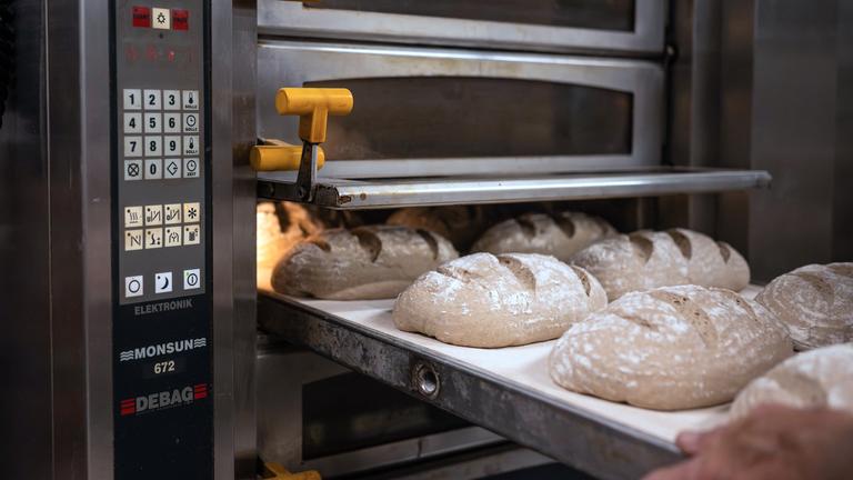 Die Ofensteuerung zeigt die Einstellungen für Temperatur und Backzeit, während die Brote auf einem Backblech liegen