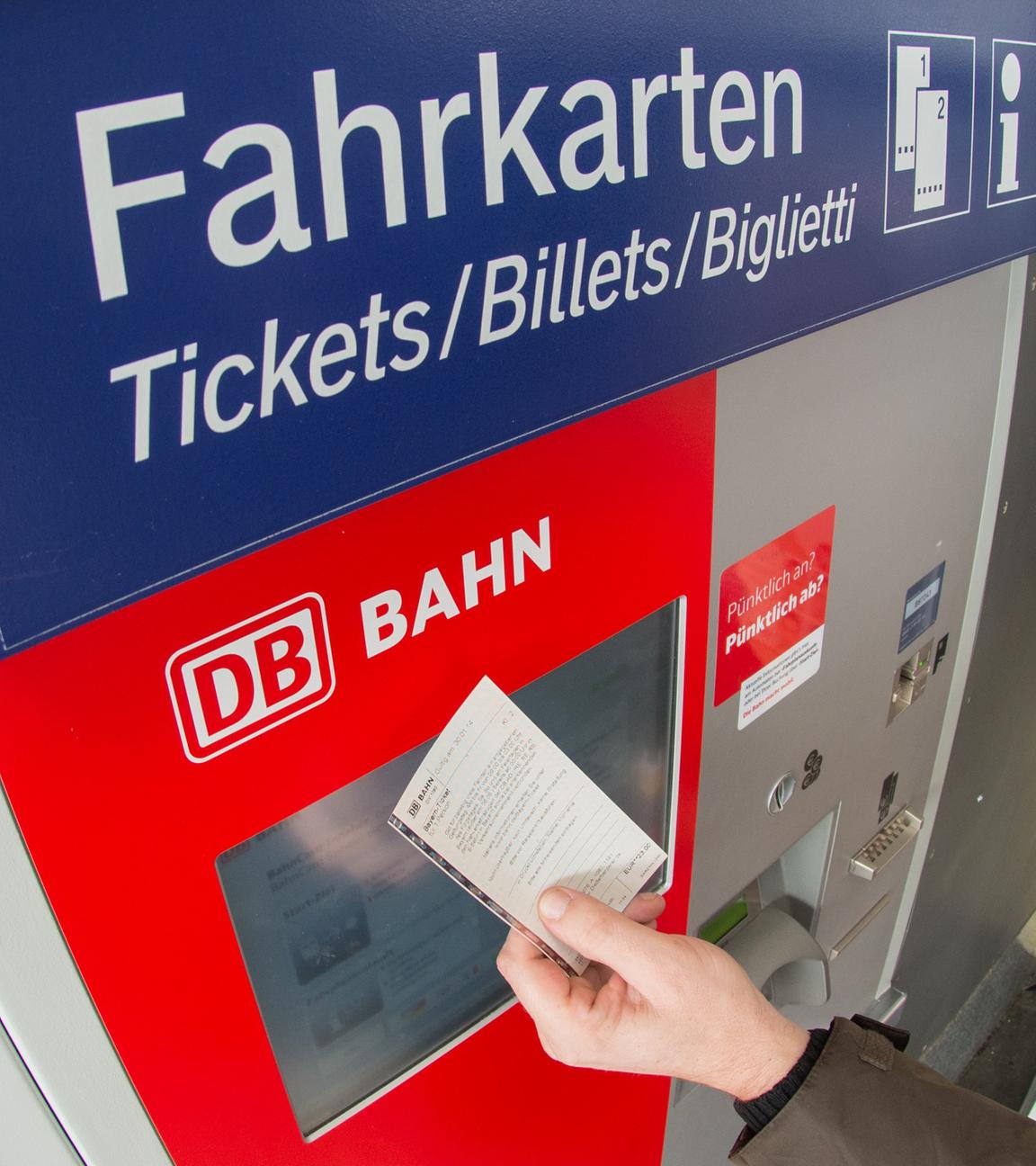 Bahn-Fahrgast mit Ticket vor einem Fahrkartenautomat