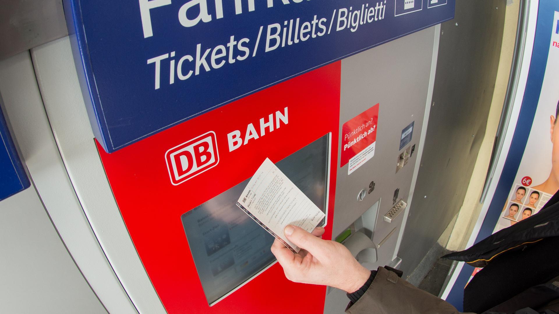 Bahn-Fahrgast mit Ticket vor einem Fahrkartenautomat