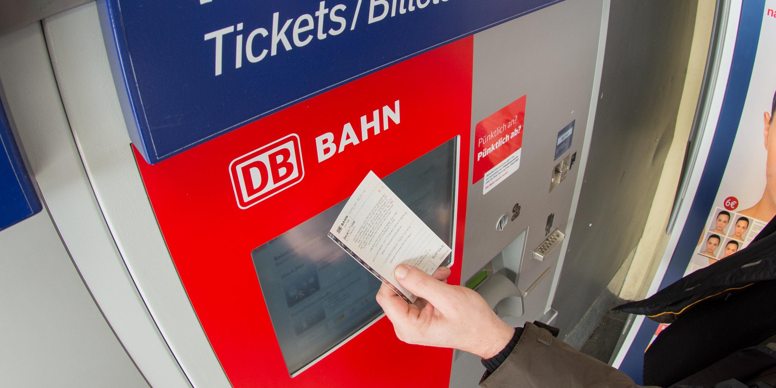 Bahn-Fahrgast mit Ticket vor einem Fahrkartenautomat