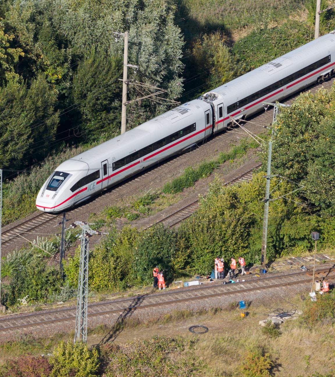  Mitarbeiter der Deutschen Bahn arbeiten nach einem Brand an einer Bahnstrecke in der Nähe eines Stellwerkes, als ein langsam fahrender verspäteter ICE der Deutschen Bahn von Berlin nach Hannover vorbeifährt.