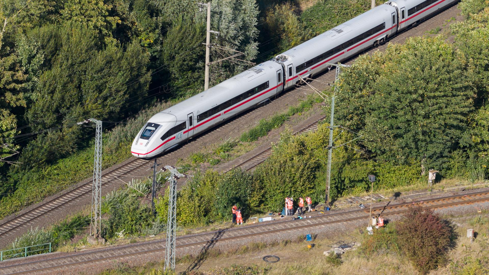  Mitarbeiter der Deutschen Bahn arbeiten nach einem Brand an einer Bahnstrecke in der Nähe eines Stellwerkes, als ein langsam fahrender verspäteter ICE der Deutschen Bahn von Berlin nach Hannover vorbeifährt.