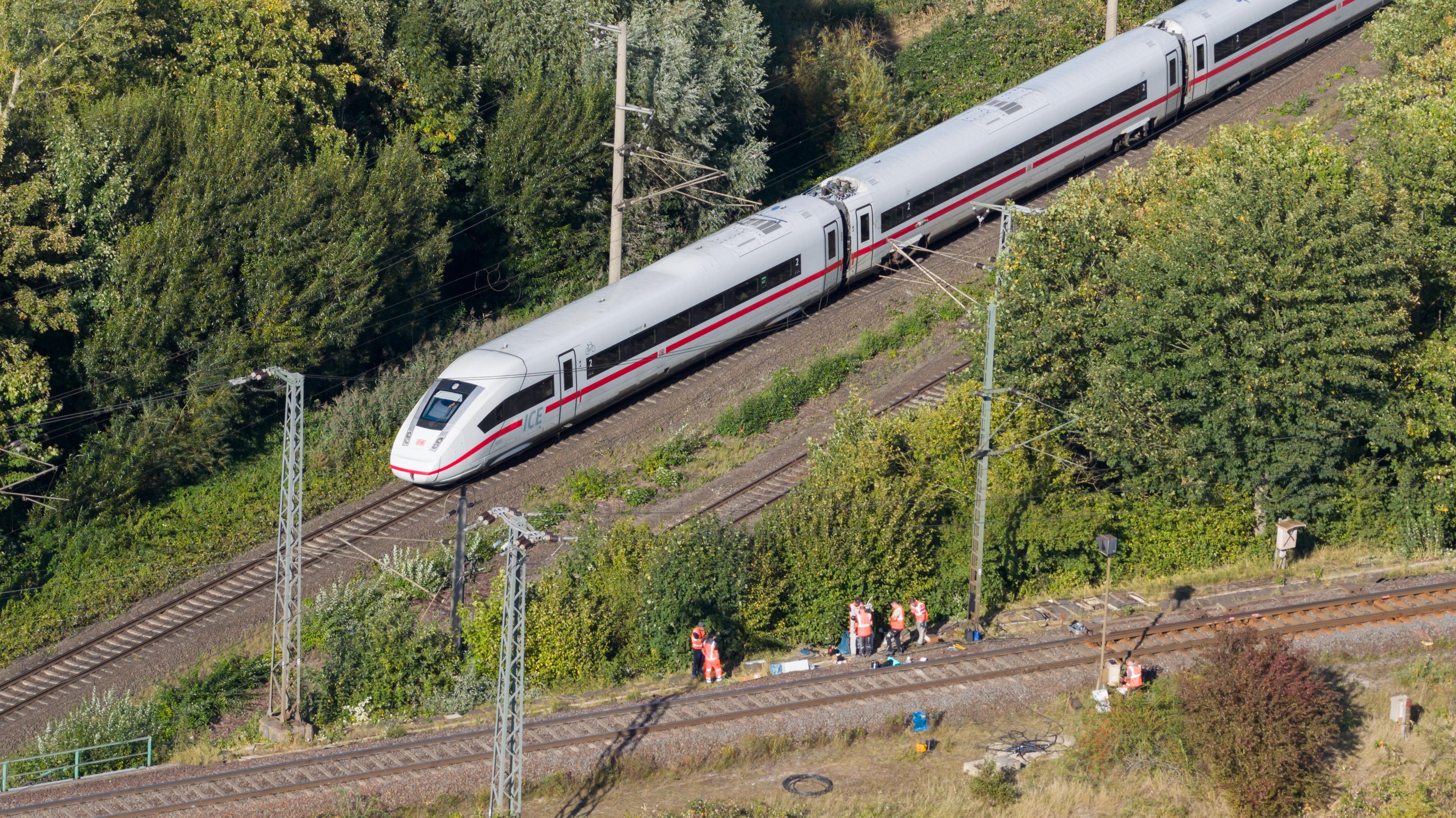  Mitarbeiter der Deutschen Bahn arbeiten nach einem Brand an einer Bahnstrecke in der Nähe eines Stellwerkes, als ein langsam fahrender verspäteter ICE der Deutschen Bahn von Berlin nach Hannover vorbeifährt.