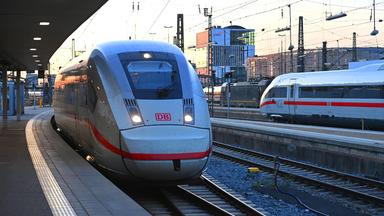 Ein ICE-Schnellzug bei der Einfahrt in das weitlaeufige Gleisvorfeld des Muenchner Hauptbahnhofs im Abendlicht.