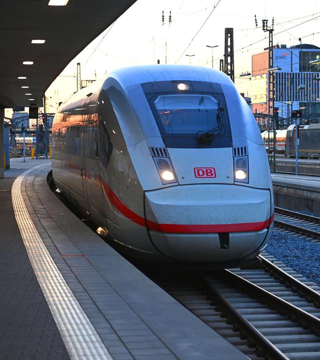 Ein ICE-Schnellzug bei der Einfahrt in das weitlaeufige Gleisvorfeld des Muenchner Hauptbahnhofs im Abendlicht.