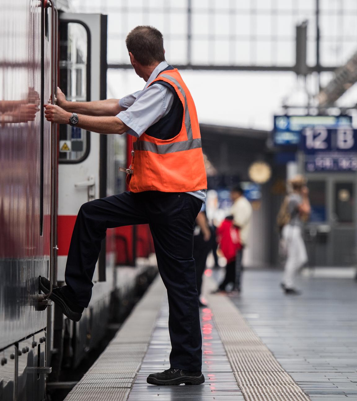 Ein Mitarbeiter der Deutschen Bahn steht im Hauptbahnhof neben einer Lokomotive.