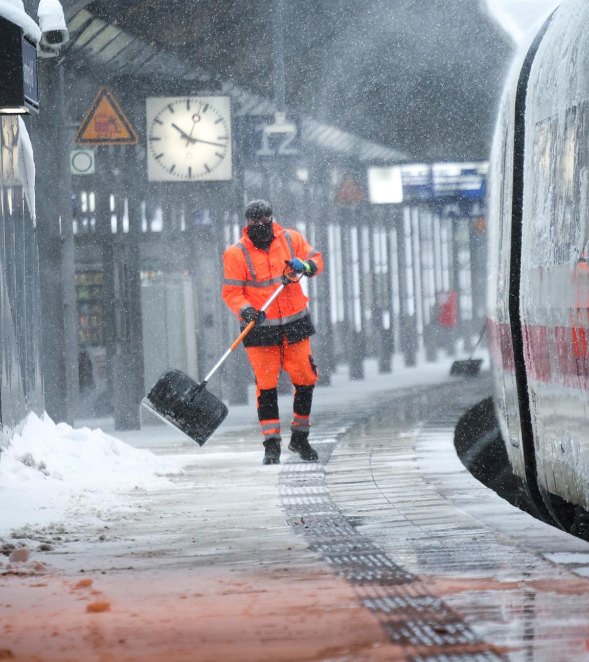 Mitarbeiter der Bahn schieben Schnee von einem Bahnsteig am Hamburger Hauptbahnhof.