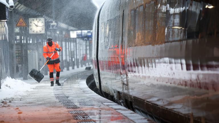 Mitarbeiter der Bahn schieben Schnee von einem Bahnsteig am Hamburger Hauptbahnhof.