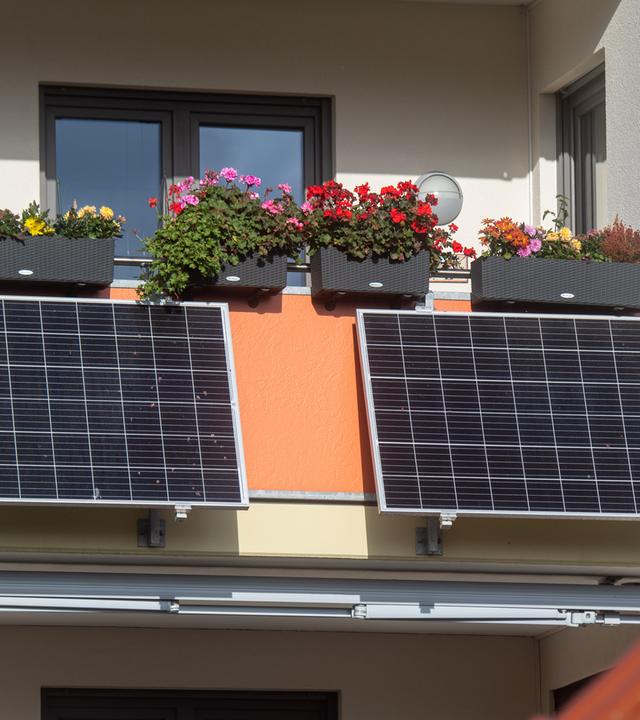 Symbolbild: Solarmodule für ein sogenanntes Balkonkraftwerk hängen an einem Balkon.