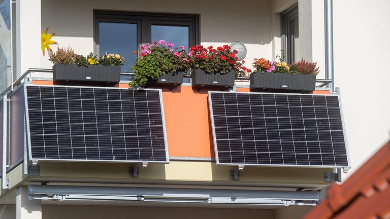 Symbolbild: Solarmodule für ein sogenanntes Balkonkraftwerk hängen an einem Balkon.