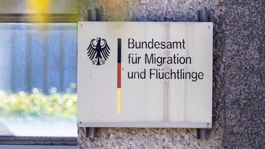 Ein Schild mit Bundesadler und den Farben Schwarz-Rot-Gold weist auf das Bundesamt für Migration und Flüchtlinge (BAMF) hin.