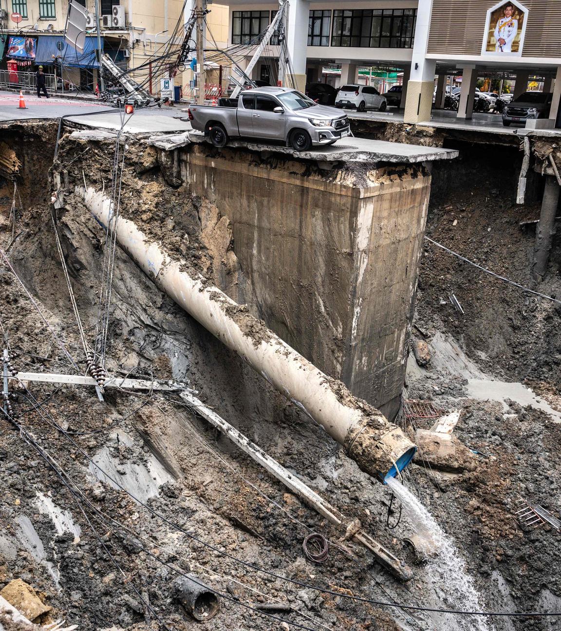 A vehicle is seen on the edge of a hole in the ground after a road collapsed near a hospital in Bangkok on September 24, 2025. 